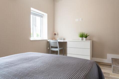 Bright, neutral bedroom with a comfortable doub...