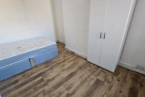 A small, simple room with a basic bed and wardr...