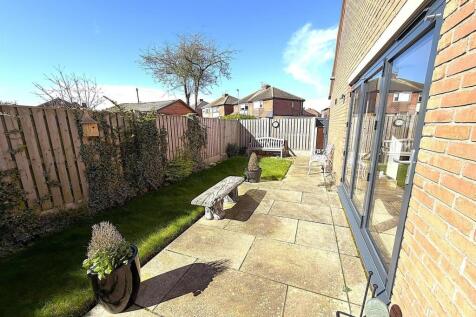 Sunny patio area with well-maintained lawn...