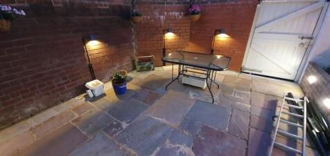 Cozy lit paved patio with table and plants...
