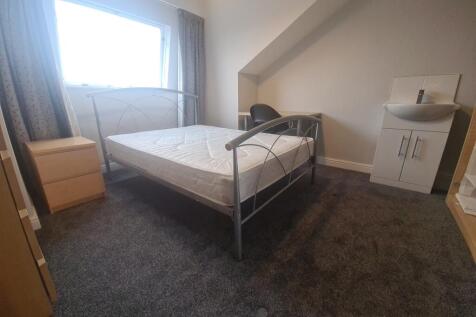 A spacious double bedroom featuring a large bed...