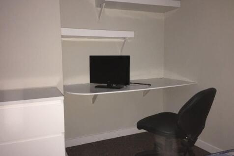 Compact bedroom corner with a built-in wall des...