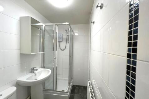 Bright, modern bathroom with a corner shower en...
