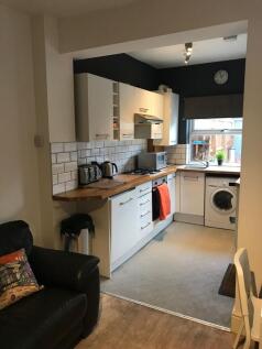 Modern open-plan kitchen with white cabinets, w...