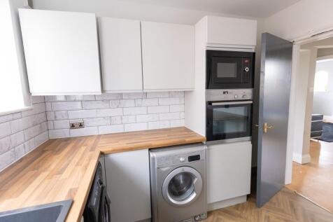 Modern student kitchen featuring white cabinets...