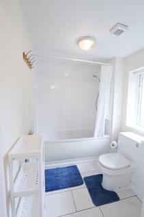 Bright, modern bathroom with a white tiled bath...