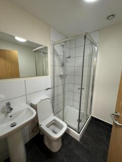 Neat, modern bathroom with a corner glass showe...