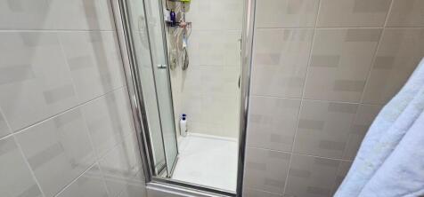 Clean tiled shower cubicle with glass door...