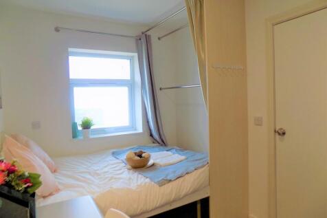 A cozy, bright single bedroom featuring a neatl...