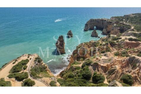 Drone view of iconic sea stacks and natural rock arch in Carvoeiro, Algarve, located steps away from a charming 4-bedroom villa for sale.