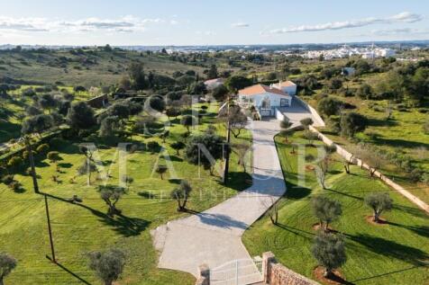 Aerial view of a brand new luxury single-storey villa for sale near Estômbar Algarve, featuring a long driveway, 10,000 sqm plot, and professionally landscaped country gardens.