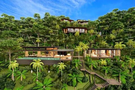 A modern hillside villa is nestled among lush gree