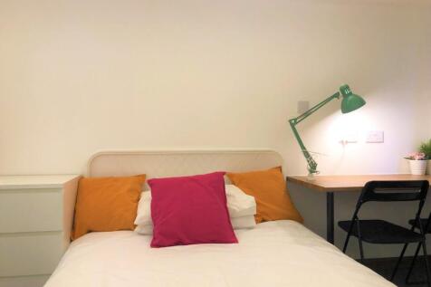 A cozy and tidy single bedroom featuring a whit...