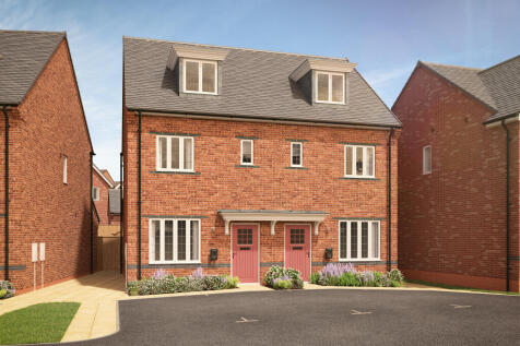 A pair of modern brick townhouses with pink doors and dormer windows stand in the foreground