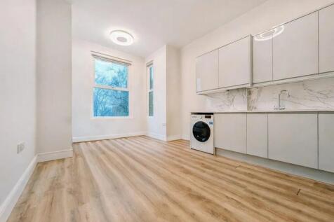 Bright, modern kitchen area with sleek white ca...