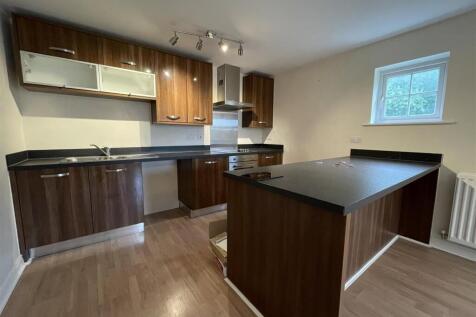 Modern kitchen with island and dark wood units...
