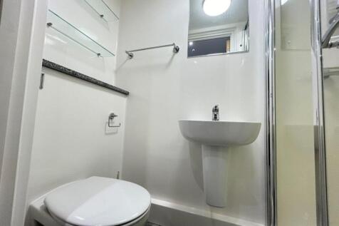 Clean modern ensuite with sleek glass shelving...