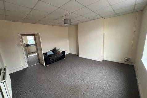 A spacious living room with neutral walls and a...