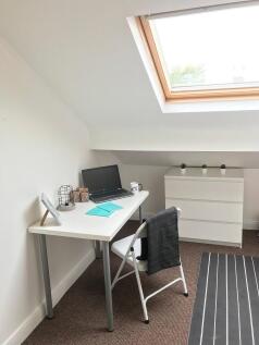 Bright, neatly furnished attic workspace with a...