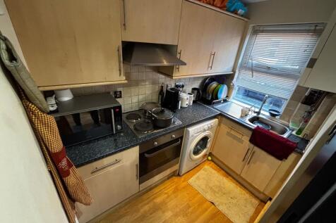 Compact fitted kitchen with light wood cabinets...