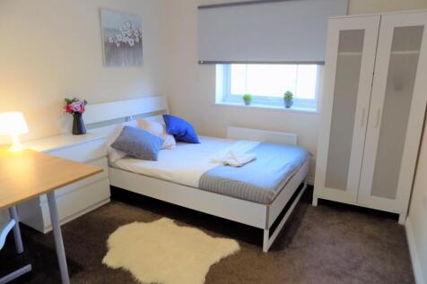 Bright, neatly furnished bedroom with a double ...