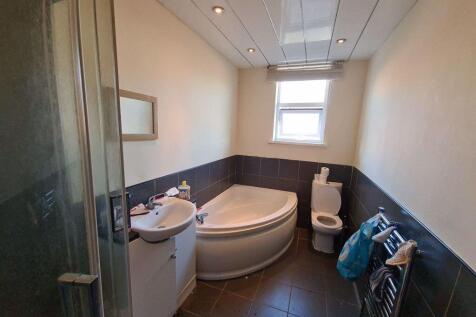 A modern bathroom suite featuring a corner bath...