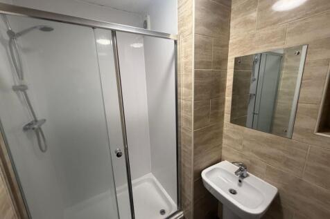 Modern tiled bathroom with a glass-enclosed sho...