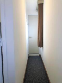 A clean, narrow hallway with neutral walls and ...