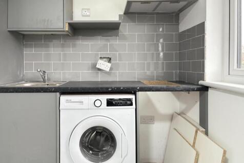 Compact kitchen with modern grey cabinets, tile...