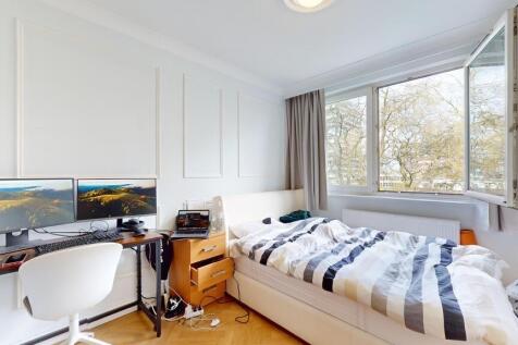 Bright bedroom with dual monitors and leafy vie...