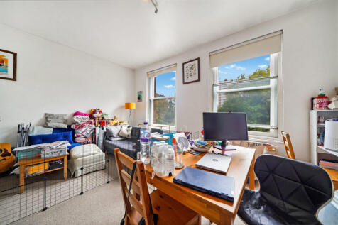 Messy living room and workspace with a wooden desk
