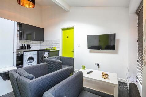 Bright lounge with wall-mounted TV and kitchen...