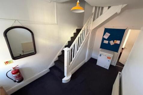 Bright, functional entryway with white staircas...