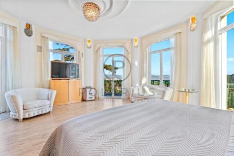 Bright bedroom with large windows, a bed, chairs, 