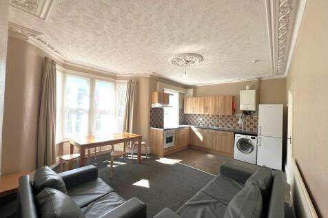 Bright open-plan living area with a bay window,...