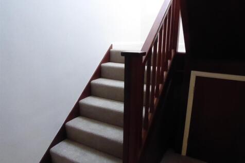 Bright carpeted staircase with wood banister...