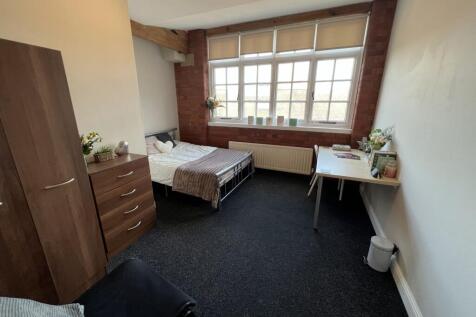 A well-lit, cozy single bedroom with a large wi...