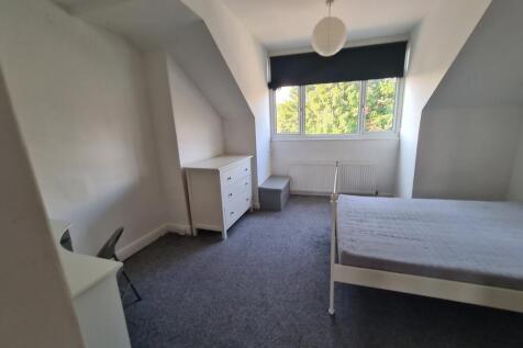 A bright and tidy bedroom featuring a large win...