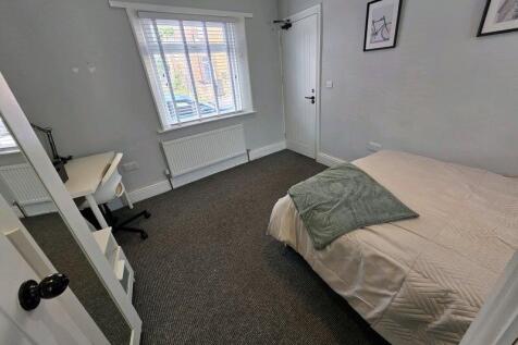 A neat and tidy single bedroom featuring a comf...