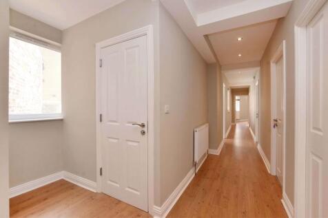 Bright, freshly painted hallway with warm wood-...