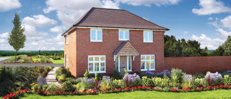 A red brick detached house with white-framed windows and a small porch, surrounded by colourful gard