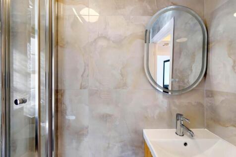 Contemporary tiled bathroom featuring a glass-e...