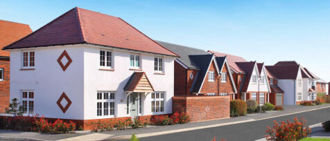 Modern residential houses with white and red brick facades, covered with pitched roofs, along a clea