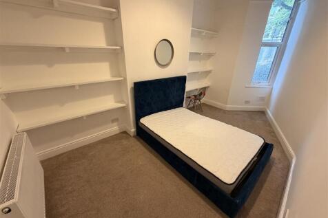 Bright bedroom with plush bed and ample shelvin...