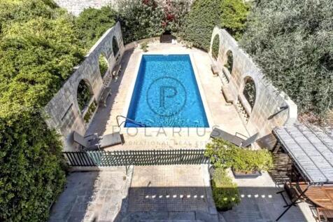 A rectangular swimming pool is surrounded by stone