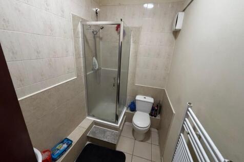Compact tiled bathroom with a corner shower cub...