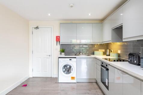 Modern fitted kitchen with glossy pale grey cab...