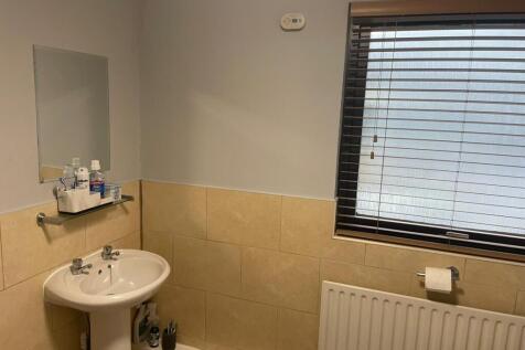 Clean, neutrally tiled bathroom with a pedestal...