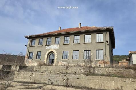 Front view of the historic school building showing its symmetrical windows and arched entrance