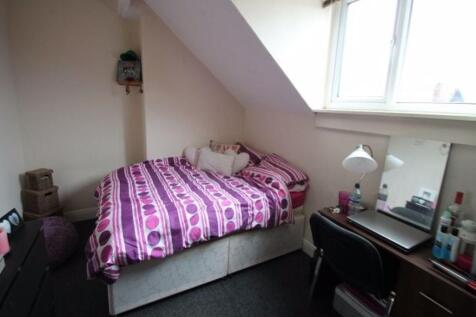 A cozy single bedroom with a purple patterned b...